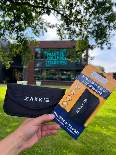 ’t Zakkie in de hand voor een schoolgebouw