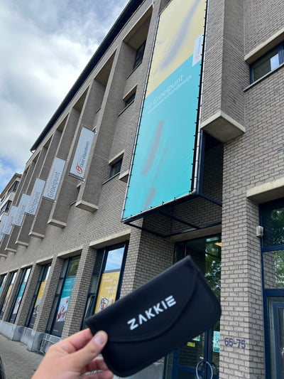 ’t Zakkie in de hand bij een onderwijsgebouw